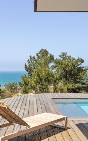 Piscine sur-mesure avec terrasse en bois et vue sur la mer, projet réalisé par Nymfeo.